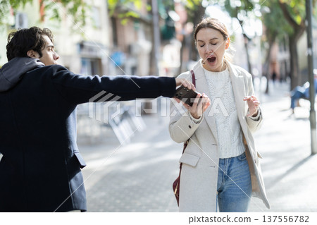 Young man snatches phone from woman on street 137556782