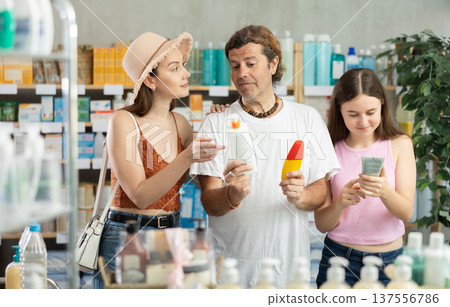 Father, mother and daughter choose sunscreen together at drugstore Father, mother and daughter choose sunscreen together at drugstore 137556786