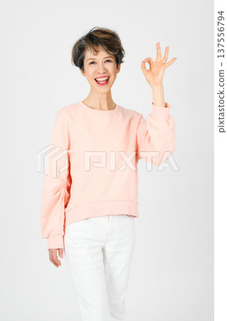 一位五十多歲的女性在白色背景下用左手比出「OK」手勢。 137556794