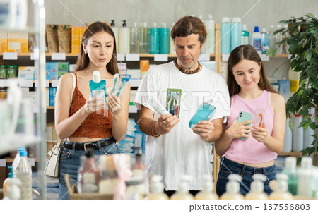 Father, mother and daughter choose toothbrushes together at drugstore Father, mother and daughter choose toothbrushes together at drugstore 137556803