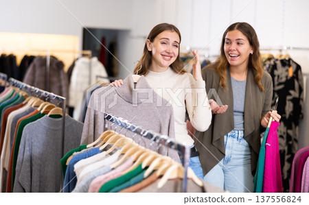 Portrait of two positive women choosing cardigan in clothing shop 137556824