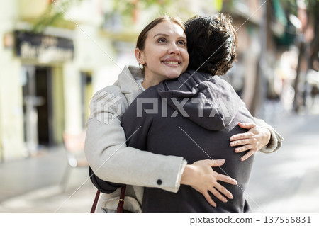 Man and woman hug as they meet on a street in spring city. 137556831