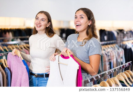 Shopping room of clothing shop with young women choosing jackets and sweater Shopping room of clothing shop with young women choosing jackets and sweater 137556849