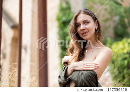 Woman in unbuttoned blouse posing near fence 137556856