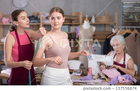 adult female dressmaker takes measurements for a client in the workshop 137556874
