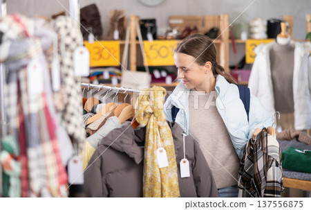 Teenage girl choosing something for autumn-winter in clothing store 137556875