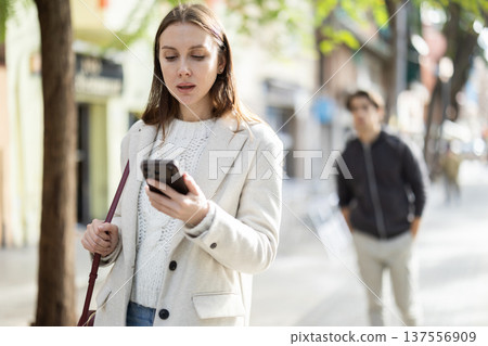 Portrait of woman with mobile phone walking along the street of spring city 137556909
