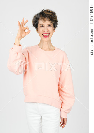 A woman in her 50s making an OK sign with her right hand on a white background 137556913