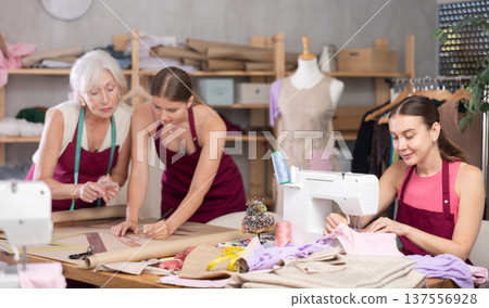 Woman tailor sewing, senior and young employee assistant drawing paper dress pattern by curves 137556928
