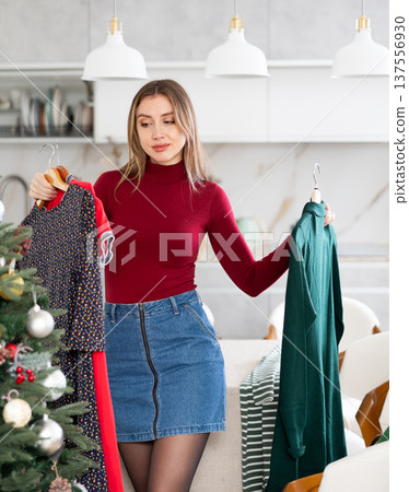 Young upset woman choosing which dress to wear Young upset woman choosing which dress to wear 137556930
