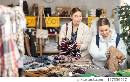 Woman with daughter choosing a sweater near the counter Woman with daughter choosing a sweater near the counter 137556937