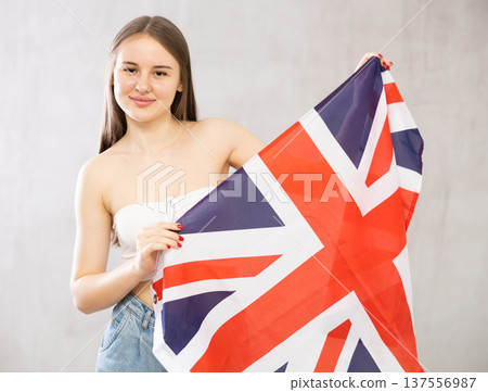 Girl holds unfolded canvas flag of Great Britain in front of her 137556987