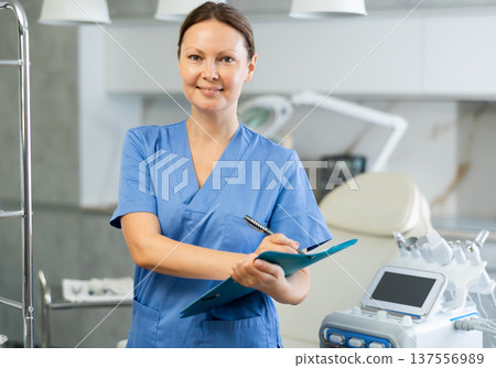 Adult female cosmetologist taking notes in medical room 137556989