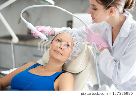 Adult woman getting oxygen face therapy in beauty salon. Professional skin care treatment, atomized nutrients to Supplement, skin nutrition. Innovative technique Adult woman getting oxygen face therapy in beauty salon. Professional skin care treatment, atomized nutrients to Supplement, skin nutrition. Innovative technique 137556990