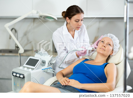 Adult woman getting oxygen face therapy in beauty salon. Professional skin care treatment, atomized nutrients to Supplement, skin nutrition. Innovative technique 137557020