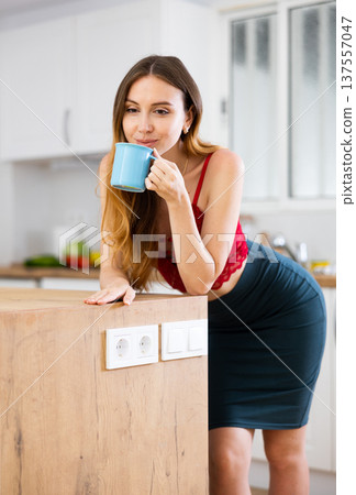 Woman drinking coffee at kitchen in morning 137557047