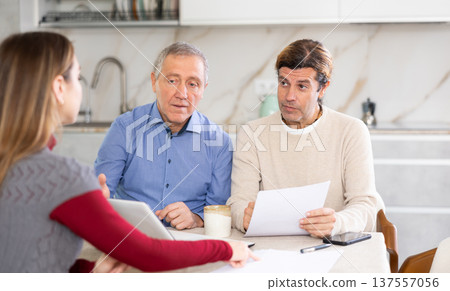 Two men listen attentively to saleswoman talking about the advantages of taking out microloan from credit institution Two men listen attentively to saleswoman talking about the advantages of taking out microloan from credit institution 137557056