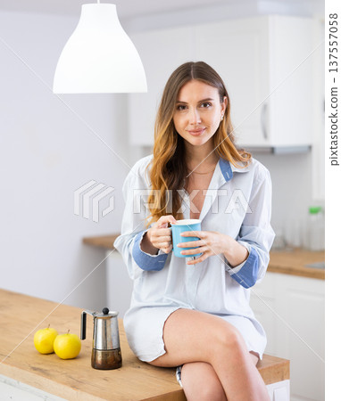 Cheerful woman drinking coffee in kitchen at home 137557058