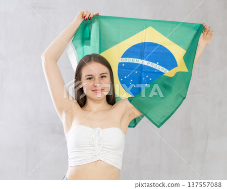 Smiling female football fan holding Brazilian flag 137557088