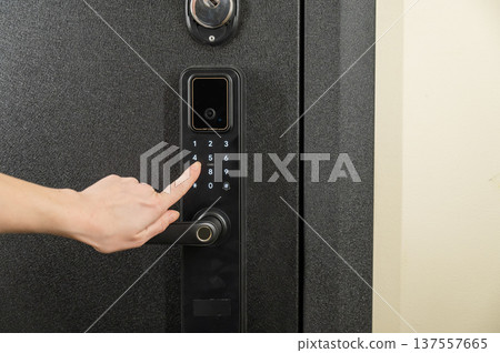 A woman opens a modern smart door lock with a digital keypad using a code. 137557665