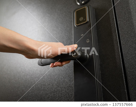 A woman opens a modern smart door lock with a digital keypad and biometric fingerprint access. 137557666