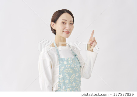 Woman wearing an apron pointing to the right, white background 137557829
