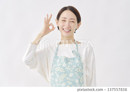 Woman wearing an apron OK sign White background 137557838