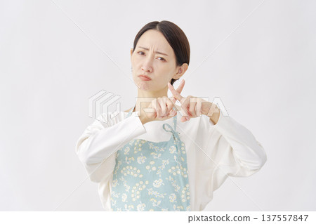 一位身穿圍裙的女子在白色背景上做出十字手勢。 137557847