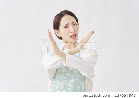 一位身穿圍裙的女子在白色背景上做出十字手勢。 137557848