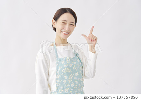 Woman wearing an apron making a check sign gesture on a white background Woman wearing an apron making a check sign gesture on a white background 137557850