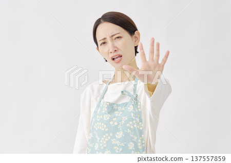 一位身穿圍裙的女子在白色背景上做出停止手勢 137557859