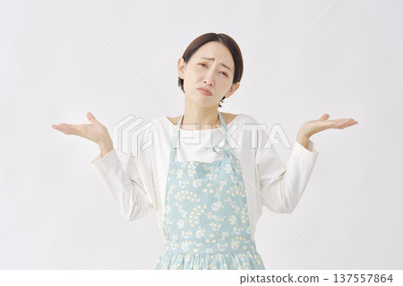 Woman wearing an apron making a gesture of giving up on a white background Woman wearing an apron making a gesture of giving up on a white background 137557864