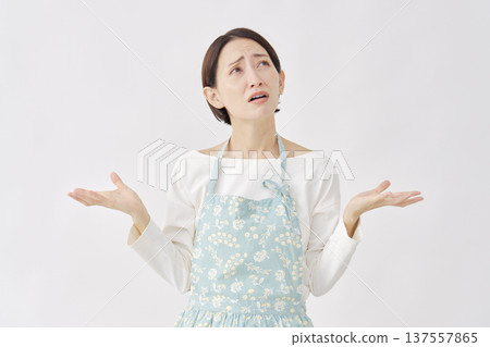 Woman wearing an apron making a gesture of giving up on a white background Woman wearing an apron making a gesture of giving up on a white background 137557865