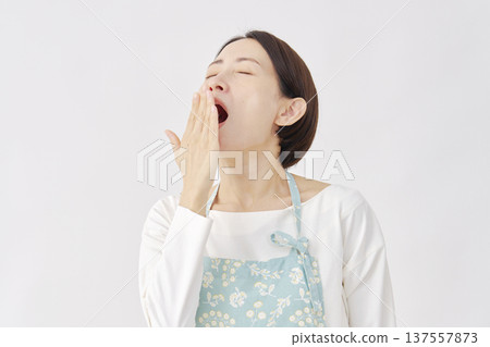 Woman wearing an apron yawning white background Woman wearing an apron yawning white background 137557873