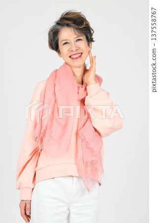 一位五十多歲的女性用左手摀著臉頰，背景為白色。 137558767