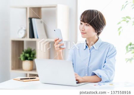 A middle-aged woman working remotely from home. A middle-aged woman working remotely from home. 137558916
