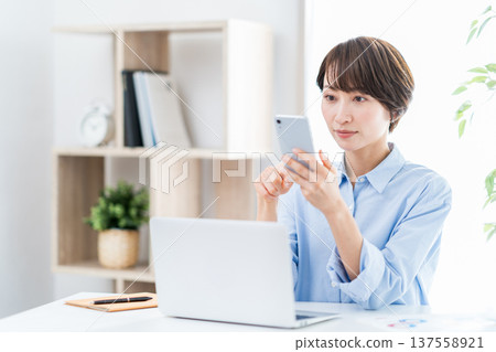 A middle-aged woman working remotely from home. A middle-aged woman working remotely from home. 137558921