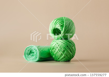 Eco-friendly textile thread and roll of green trash bags made from recycled plastic. The concept of recycling secondary raw materials, conscious waste management Eco-friendly textile thread and roll of green trash bags made from recycled plastic. The concept of recycling secondary raw materials, conscious waste management 137559277