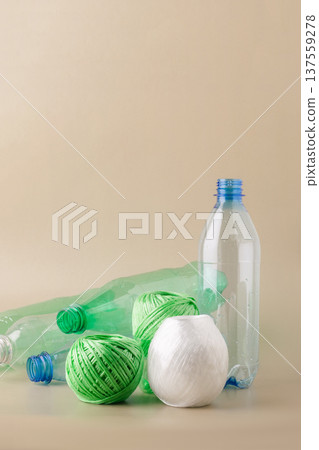 Plastic bottles balls of yarn on light background, symbolizing the eco-friendly process of recycling waste into textiles. Sustainable living, plastic recycling, reuse 137559278