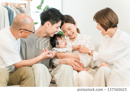 Mother holding baby on sofa in living room, three-generation family, family (first grandchild, grandchild) 137560025