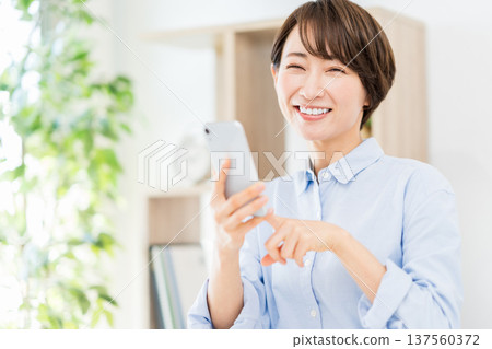 在客廳裡操作智能手機的中年婦女。 137560372