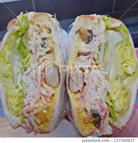 Delicious sandwich filled with fresh ingredients like crisp vegetables, tender meats, and savory spreads, all between two slices of soft bread. Perfect for a quick and satisfying meal. 137560637