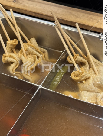 Odeng, a popular Korean street food made from seasoned fish cake, skewered and served in a warm, savory broth. Often paired with dipping sauces, it's a comforting and flavorful snack enjoyed anytime. 137560653