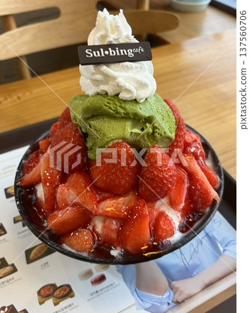 Soft and fluffy strawberry bingsu with finely shaved ice, sweet strawberry syrup, and fresh strawberry slices. A refreshing and delightful Korean dessert, perfect for a cool and fruity treat. 137560706