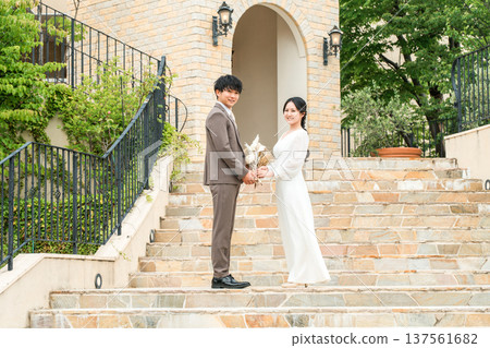 新郎新娘手捧花束，面對面站著（婚禮，新娘，情侶） 137561682