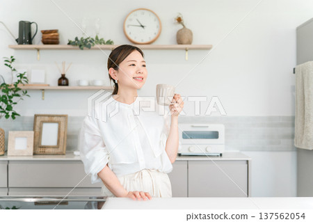 一位女士在廚房喝咖啡、茶和熱水。 一位女士在廚房喝咖啡、茶和熱水。 137562054