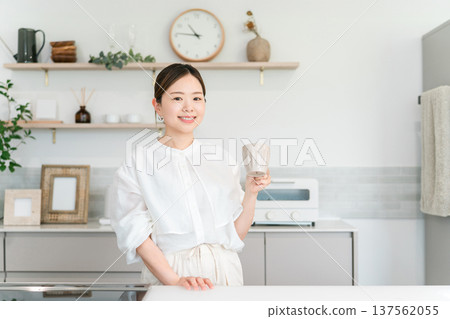 A woman drinking coffee, tea, and hot water in the kitchen A woman drinking coffee, tea, and hot water in the kitchen 137562055
