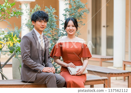 Couple in dresses sitting on chairs, married couple, bride and groom, dressed up couple, millionaire, wealthy Couple in dresses sitting on chairs, married couple, bride and groom, dressed up couple, millionaire, wealthy 137562112