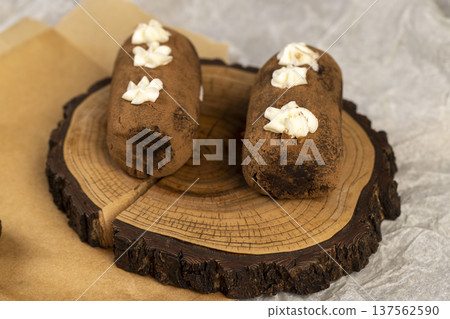 a black potato cake lies on a serving board and paper, a sweet classic cake made from butter and a cocoa mixed with sponge cake and cognac a black potato cake lies on a serving board and paper, a sweet classic cake made from butter and a cocoa mixed with sponge cake and cognac 137562590