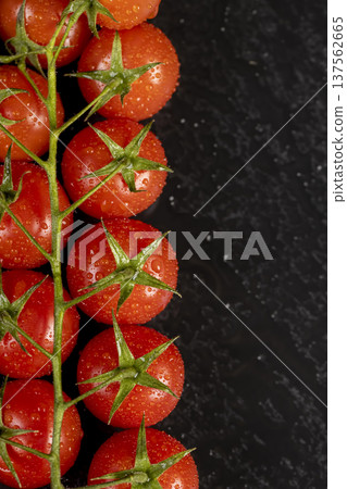 wet ripe red round tomatoes on a black slate board, sweet fresh round tomatoes covered with water droplets lie on a black after harvesting 137562665